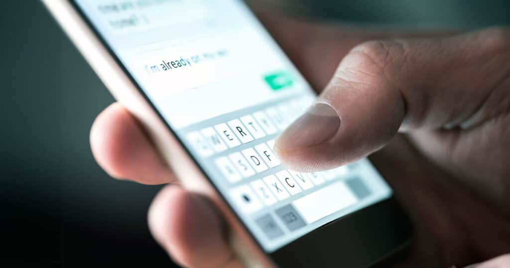 Man typing text message on mobile phone